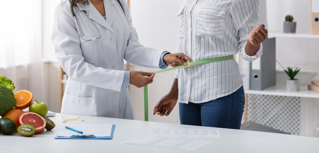 Cropped of doctor measuring patient body with tape
